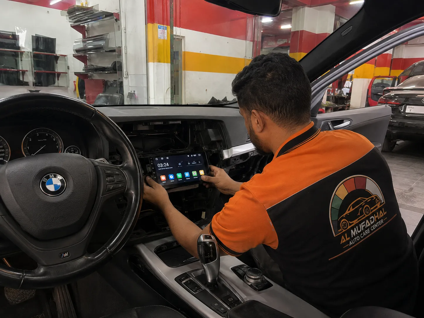 AL MUFADHAL technician installing and testing an Android multimedia unit in a BMW