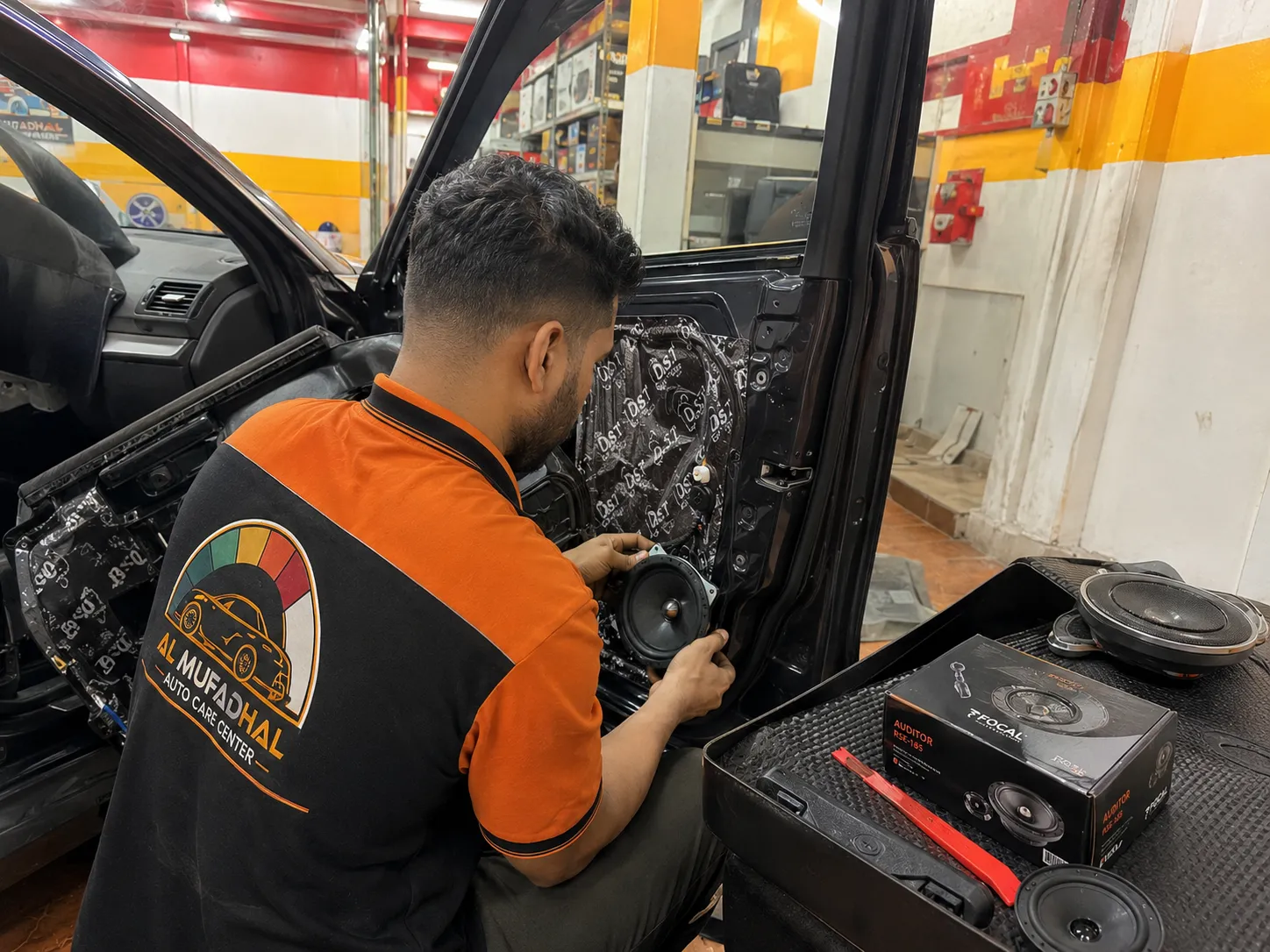 AL MUFADHAL technician fitting a new door speaker with sound damping installed